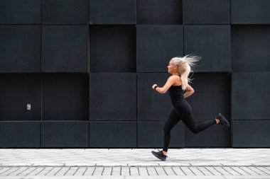 Sportif genç kadın hızlı minimalist kent ortamında çalışan yan görünüm