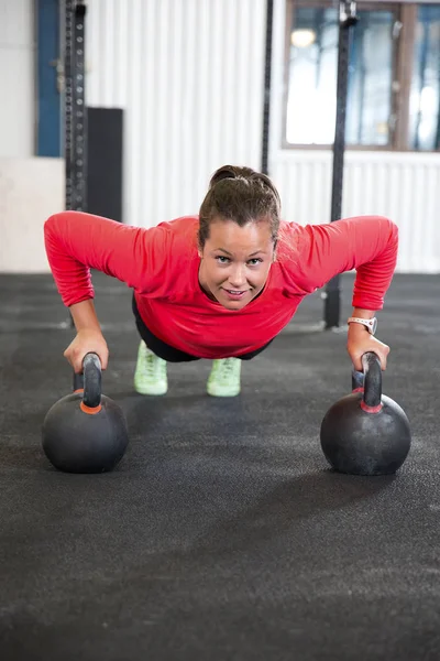 헬스 클럽에서 Kettlebell에 팔 굽 혀 펴기를 하 고 여자를 맞게 — 스톡 사진