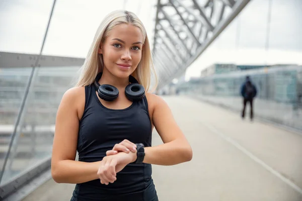 Corredor urbano femenino comprobando el rastreador de reloj inteligente en el puente —  Fotos de Stock