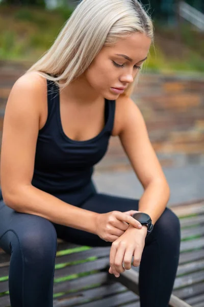 Mujer tomando un descanso después del entrenamiento y comprobando el tiempo en Smartwat —  Fotos de Stock