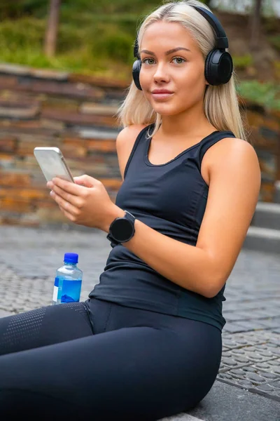 Mujer joven deportiva escuchando música con auriculares y Smartphon —  Fotos de Stock