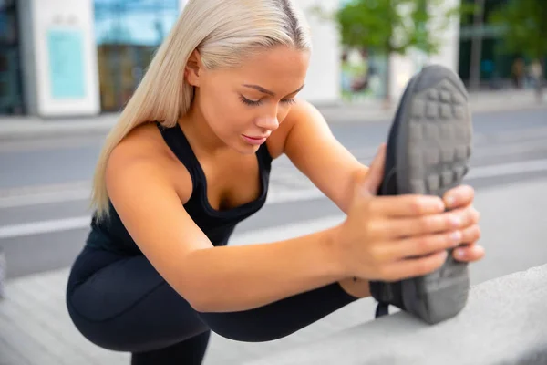 Schöne städtische Frau streckt ihr Bein vor dem Sport — Stockfoto