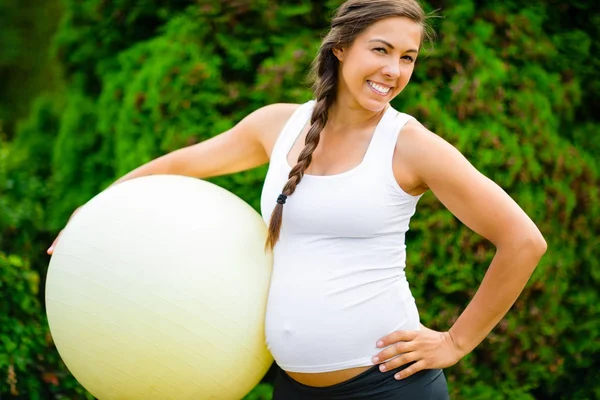 Уверенная в себе женщина с шаром для упражнений, стоящая в парке — стоковое фото