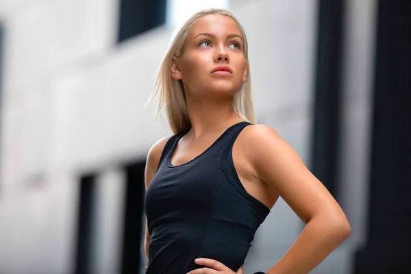 Portrati de la mujer segura de fitness en traje de entrenamiento de pie en la ciudad — Foto de Stock