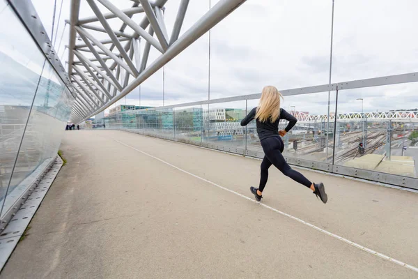 Бегунья во время беговых упражнений в современном городе в пасмурный день . — стоковое фото