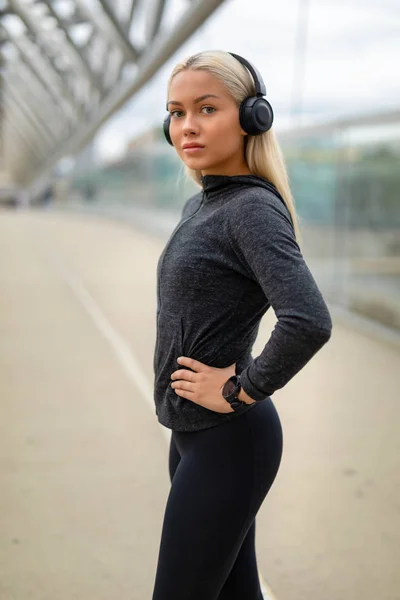 Primer plano de la mujer en traje de entrenamiento negro Escuchar música en los auriculares —  Fotos de Stock