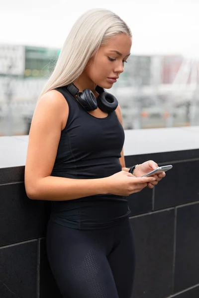 Atleta mulher desportiva usando Smartphone na ponte na cidade — Fotografia de Stock