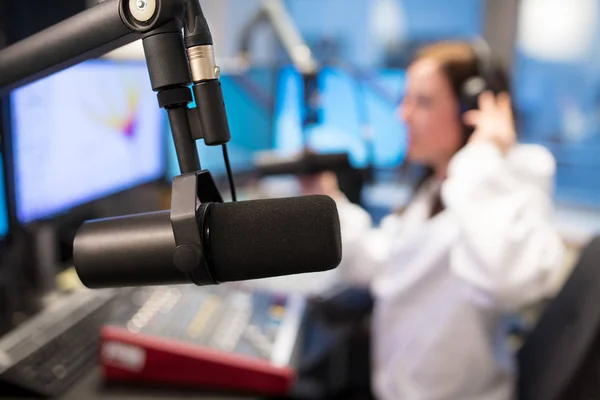 Micrófono de estudio en la estación de radio con host femenino en segundo plano — Foto de Stock