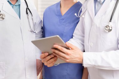 Doktor ve tıbbi ekip tablet bilgisayarda hastanede hasta raporu tartışıyor