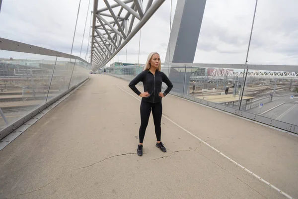 都市の現代橋に立っている美しい女性アスリート — ストック写真