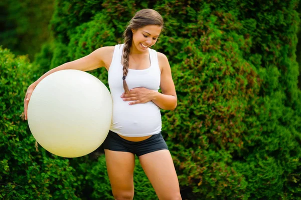 Mosolyogva terhes nő hasa megható tartva Fitness labda — Stock Fotó