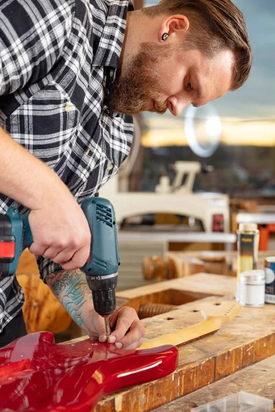 Porträt eines Handwerkers, der in einer Werkstatt mit Gitarre arbeitet — Stockfoto