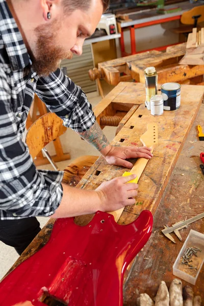 Primer plano de un artesano lijando un cuello de guitarra en madera en el taller — Foto de Stock