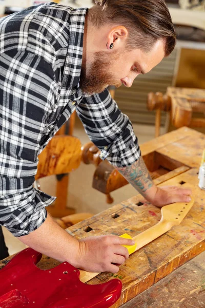 Primer plano del artesano lijando un cuello de guitarra en madera en el taller — Foto de Stock