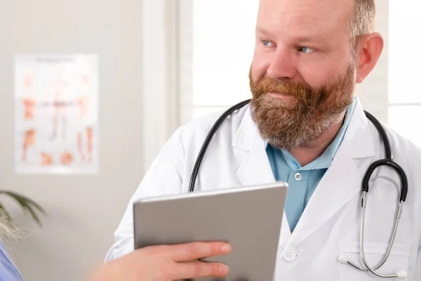 Læger diskuterer rapport om en patient på tablet computer på hospitalet - Stock-foto