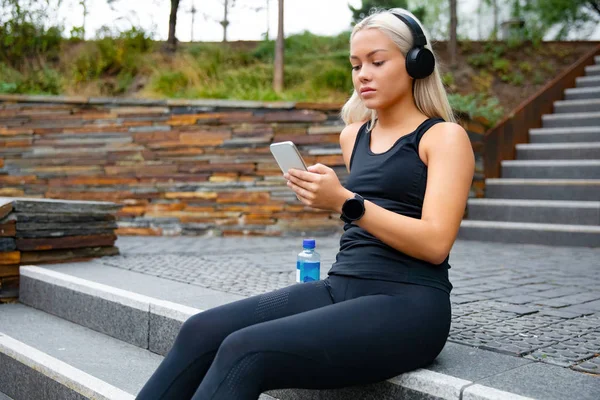 Hermosa mujer deportiva sentada en las escaleras escuchar música desde el teléfono inteligente —  Fotos de Stock