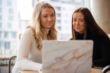 Modern kahve dükkanında ortak ödev projesi üzerinde çalışan kadın öğrenciler