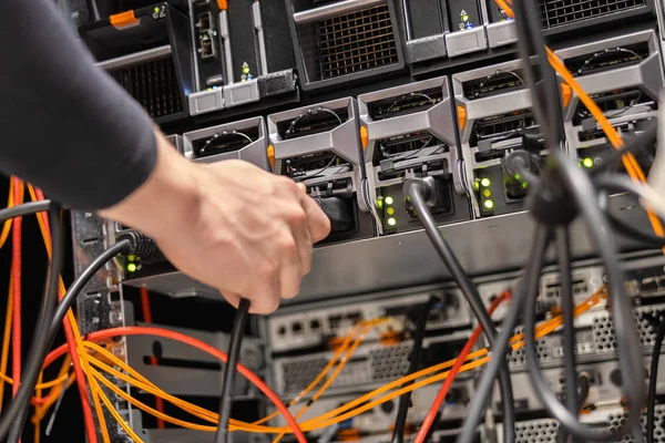 Mannelijke technicus inpluggen stroomkabel in paneel bij datacenter — Stockfoto
