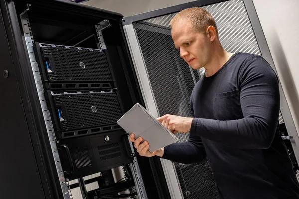 Ingenieur mit digitalem Tablet, das Server im Rechenzentrum analysiert — Stockfoto