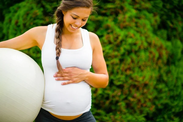 Terhes nő megható has míg Holding fitness labdát Park — Stock Fotó