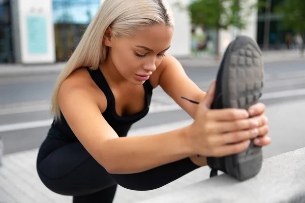 Hinreißende junge Frau beim Stretching auf dem Bürgersteig in der Stadt — Stockfoto