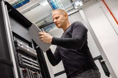 Erkek teknisyen San ve sunucuları Izlemek için Datacenter dijital tablet kullanma
