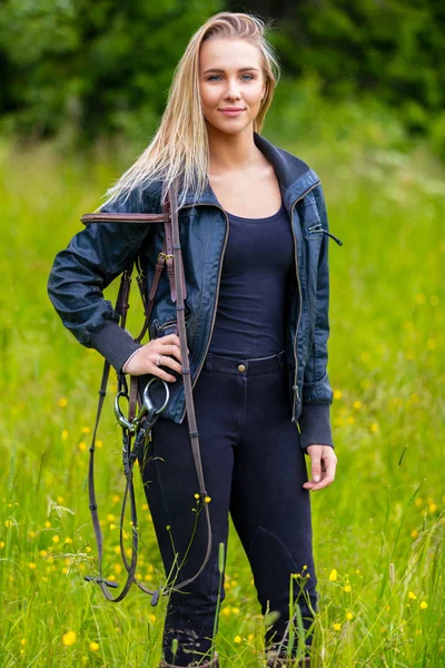 Schöne junge Reiterin steht auf einer grünen Weide — Stockfoto