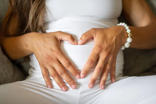 Zblízka na těhotnou ženu, která vytváří srdeční tvar na břiše — Stock fotografie