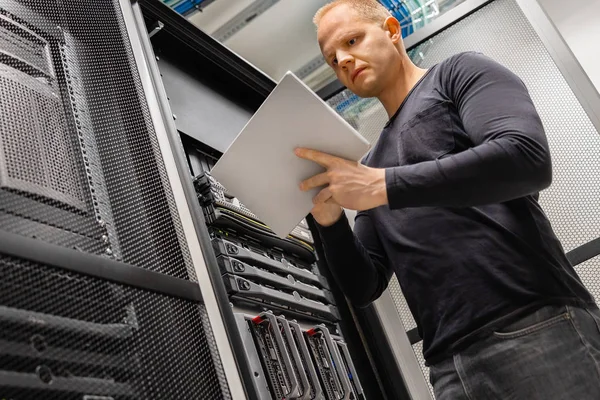 Männlicher IT-Ingenieur mit Tablet im Rechenzentrum, um Netzwerk und Server zu überwachen — Stockfoto