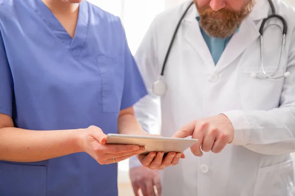 Γιατρός και νοσοκόμα συζητούν τις εξετάσεις ασθενών στον υπολογιστή ταμπλέτας στο νοσοκομείο — Φωτογραφία Αρχείου