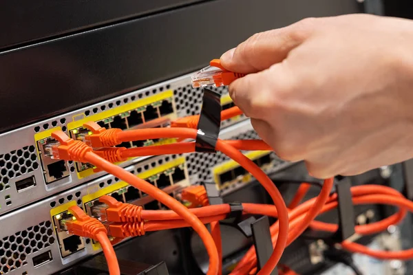 Чоловічий інженер підключення мережевого кабелю в маршрутизаторі в центрі обробки даних — стокове фото