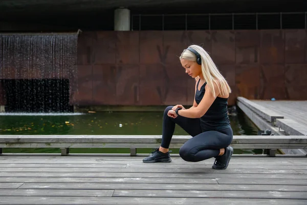 美丽的健身女人使用智能手表手机 — 图库照片