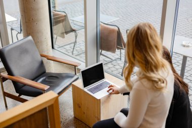 Şehirdeki restoranda dizüstü bilgisayarda proje yapan iki kadın.