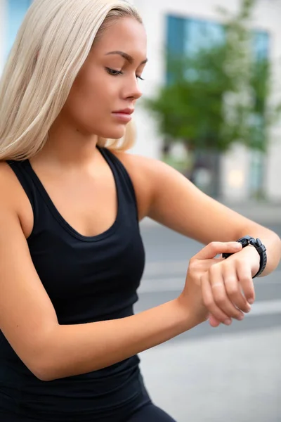 Mujer enfocada comprobando el rendimiento y el seguimiento en Smartwatch después del ejercicio —  Fotos de Stock
