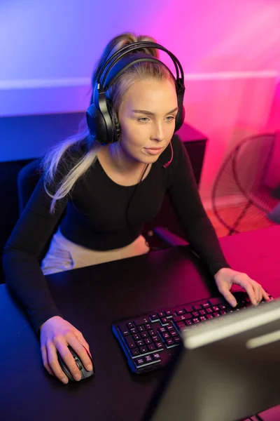 Enfocado Profesional E-sport Gamer Girl con auriculares jugando videojuego en línea en PC — Foto de Stock