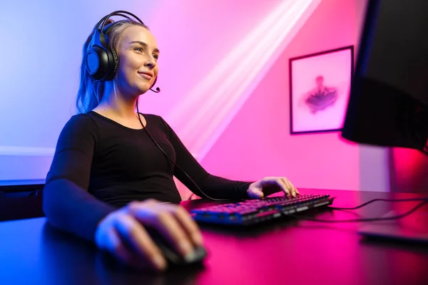Feliz y hermosa rubia gamer chica jugando video juego en línea en su computadora personal. — Foto de Stock