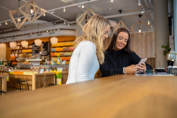 Şehirdeki Kafe 'de akıllı telefona bakan iki mutlu arkadaş.