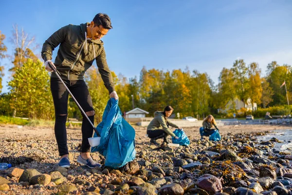 Hombre limpieza playa con voluntarios en día soleado — Foto de Stock