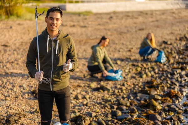 Homme montrant pouces levés avec des bénévoles protecteur de l'environnement à la plage — Photo