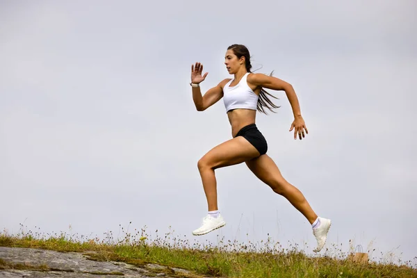 Entschlossener Athlet läuft auf Berg gegen Himmel — Stockfoto