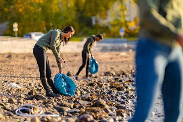Kendini adamış gönüllüler güneşli bir günde plajı temizliyor. — Stok fotoğraf