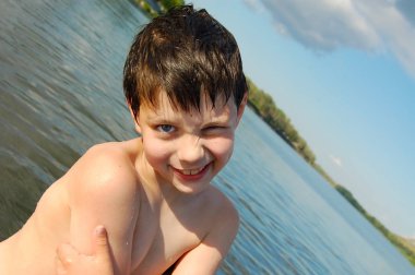 Neşeli çocuk bir nehirde yüzme ve komik gülen sonra ayakta