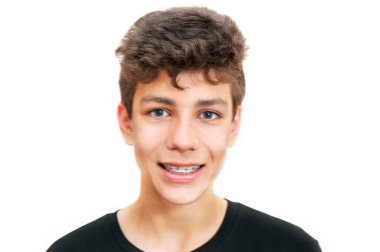 Beyaz arka planda sevimli bir çocuk. Dişlerinde, ortodontiste gittikten sonra diş telleri var. İzole edilmiş