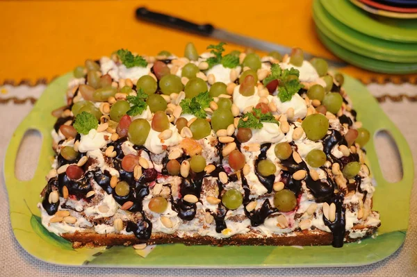 A delicious cake with nuts, grapes, cream, chocolate cooked at home