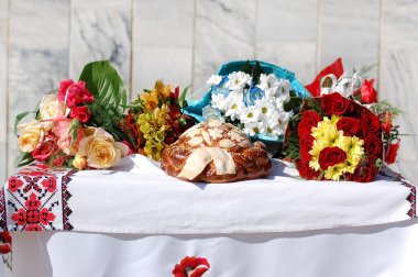 Masasında çiçek buketleri olan Ukrayna 'nın şenlikli pastanesi Bayram Ekmeği. Masa nakışlı bir havluyla kaplı.