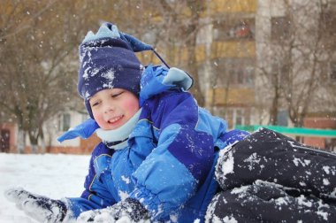 Çocuk kışın kara uzanır ve karla oynar. Böyle bir hava ve karda oynanan çocuk oyunlarıyla mutlu.