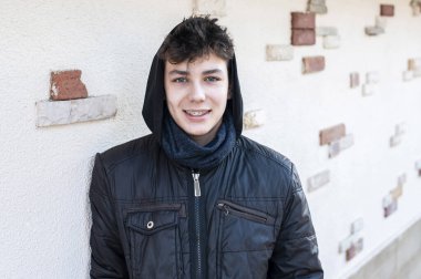 Başında başlığı olan, kışları duvarda duran ve gülümseyen sıcak ceketli genç bir çocuk. Adamın dişlerinde diş telleri olan güzel bir gülümsemesi var. Diş Konsepti