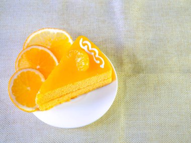 Beyaz çanak ve ahşap çatal turuncu kek masada.