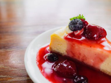 Ahşap arka plan üzerinde beyaz plaka üzerinde mix berry peynir kek