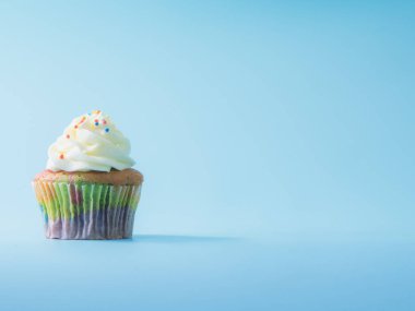 Renkli ve mavi arka plan stüdyosu nda izole giren cupcake yakın çekim.